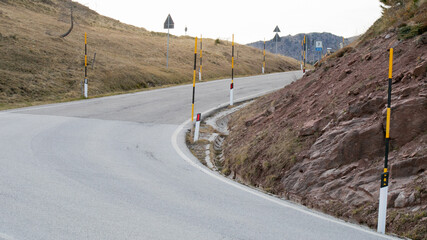 Winding mountain road with safety markers and rugged terrain symbolizing travel challenges in...