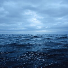 Fototapeta premium The dark blue ocean surface is dotted with small waves that gently lap against the shore, ripples on the water, ocean waves, ocean surface, gentle movement
