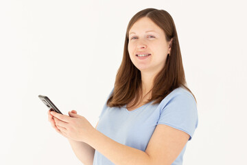 Naklejka premium Happy pretty young woman model holding smartphone looking at camera, smiling girl using mobile apps on cell phone standing isolated on white background with cellphone.