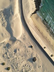 Obraz premium Aerial top down view of a coastal road through the sand dunes with sea views. Taken in Fuerteventura.