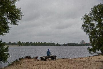 man sitting on the bench watching lake