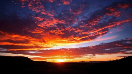 Fototapeta premium Fiery Sunset Panorama: A breathtaking view of a vibrant sunset painting the sky with fiery hues, casting a magical glow over the landscape.