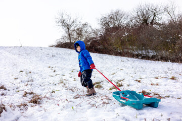 Child pulling sled in snowy winter landscape