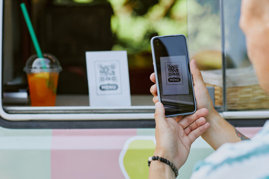 Medium close up of unrecognizable man holding smartphone with opened camera and scanning QR code with menu