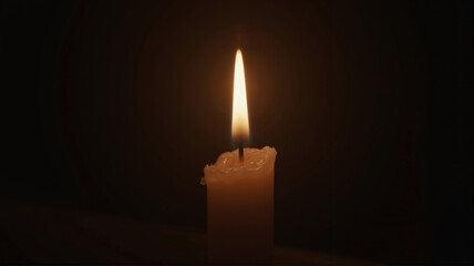Fototapeta premium One candle burning in darkness creates warm light