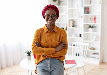 Portrait of positive young muslim african american lady in casual outfit and eyeglasses freelancer posing at workplace at home, looking at camera and smiling, panorama with copy space. Career concept