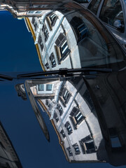 Traditional Italian urban buildings reflected in hood and windshield of car on sunny day, Rome, Italy