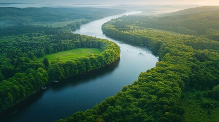 Aerial view of a winding river surrounded by lush green forests and rolling hills.