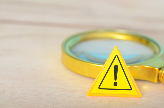 Fototapeta Investigating Caution: Close-Up of Warning Sign and Magnifying Glass in Focus