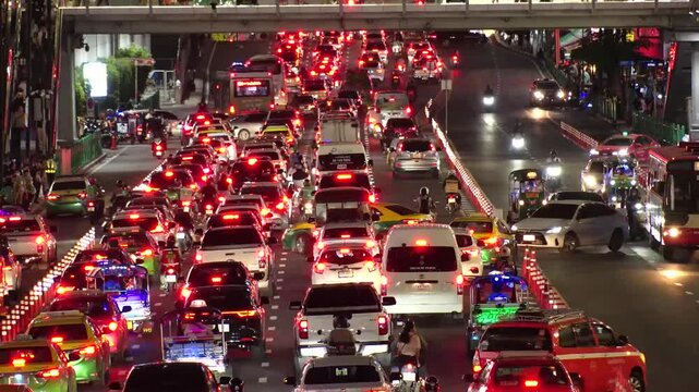 BANGKOK, THAILAND - AUGUST 2024 : High angle view of traffic jam at night. Busy rush hour at downtown shopping area. Transportation and street traffic concept video. 4K time lapse shot.