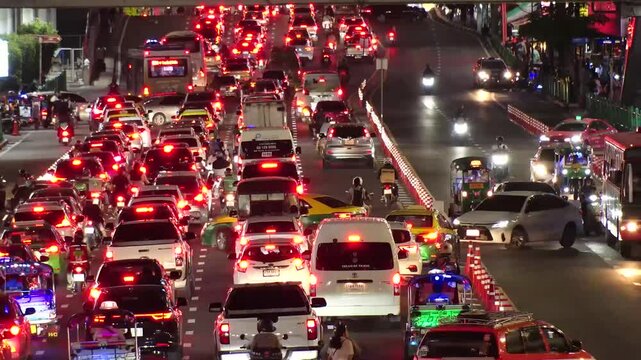 BANGKOK, THAILAND - AUGUST 2024 : High angle view of traffic jam at night. Busy rush hour at downtown shopping area. Transportation and street traffic concept video. 4K time lapse shot.