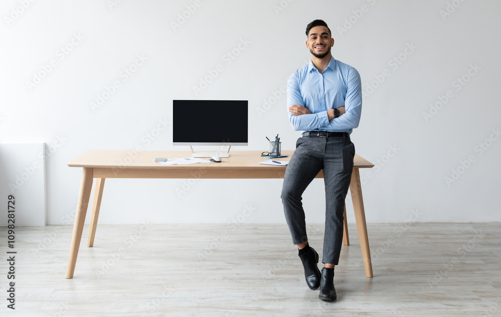 Aufkleber Mock Up Template. Happy Smiling Arab Man Sitting On Desk Posing With Folded Arms Showing Pc Computer With Blank Black Screen At Home Office, Free Copy Space. People, Technology, Remote Work Concept