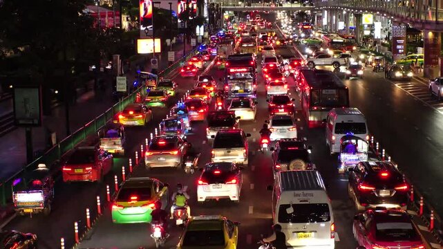 BANGKOK, THAILAND - AUGUST 2024 : High angle view of traffic jam at night. Busy rush hour at downtown shopping area. Transportation and street traffic concept video. 4K time lapse shot.