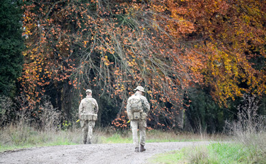 Obraz premium two British army soldiers with guns on a foot patrol in countryside