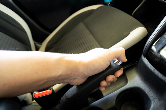 Close-up of a hand holding a car handbrake lever with chrome accents, focusing on grip and control..