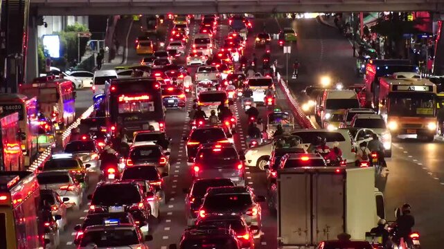 BANGKOK, THAILAND - AUGUST 2024 : High angle view of traffic jam at night. Busy rush hour at downtown shopping area. Transportation and street traffic concept video. 4K time lapse shot.