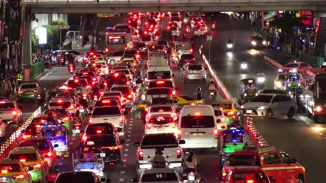 BANGKOK, THAILAND - AUGUST 2024 : 4K time lapse shot of traffic jam at night. Busy rush hour at downtown shopping area. Transportation and street traffic concept video.
