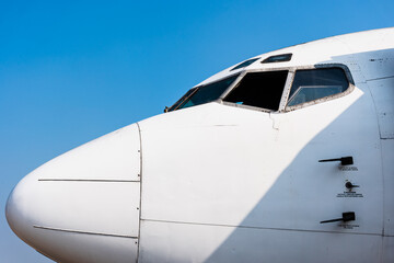 Close up of cockpit white large passenger airplane with blue sky stock photo. Side view.
