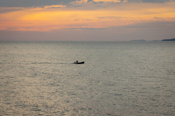 silhouette lone boat cuts through the calm waters as the sun begins its descent, casting a warm glow across the horizon