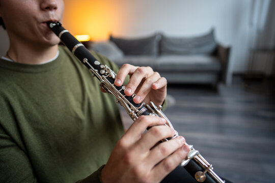Clarinet player. Clarinetist hands playing flute woodwind music instrument at home, closeup view. Musical instruments. Man plays the oboe in living room. Relaxed mental hobby concept