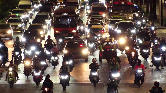 BANGKOK, THAILAND - AUGUST 2024 : High angle shot of traffic jam at night. Busy rush hour at downtown shopping area. Transportation and street traffic concept video. Slow motion shot.