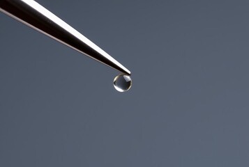 A set of precision tweezers holding a small object ;