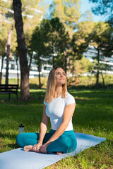 young woman sitting on yoga mat meditating in park