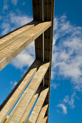 A towering, symmetrical concrete structure of a bridge extends skyward, showcasing architectural beauty in construction.