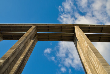 A towering, symmetrical concrete structure of a bridge extends skyward, showcasing architectural beauty in construction.
