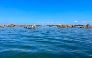 A tranquil seascape featuring beautiful rocks set beneath a clear and bright blue sky