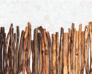 Driftwood sticks arranged in a gradient from dark to light on a white background, scattered with sea glass. A natural and textured composition showcasing craftsmanship and balance in simplicity