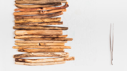 Process of arranging driftwood and sea glass sticks in a row with tweezers, highlighting craftsmanship and attention to detail. Perfect for showcasing creative organization and material presentation