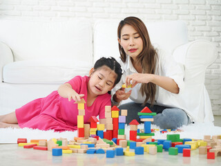 Autistic girl playing building wooden blocks with her mother.