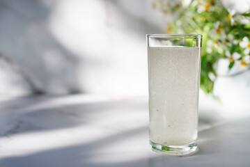 A glass of water soluble psyllium husk dietary fiber supplement on white table .