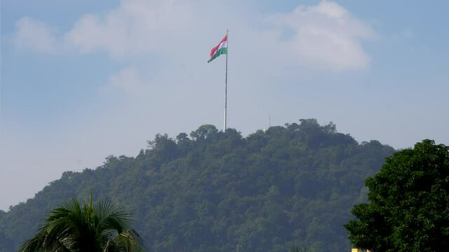 Huge Indian Flag fluttering at Gandhi Mandap hill top in Guwahati with composite shots of trees and buildings 3