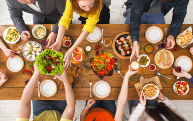 People eat healthy meals at festive table served for party. Friends celebrate with organic food on...