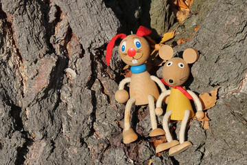 Bunny and mouse - traditional painted wooden toys perched at a tree trunk