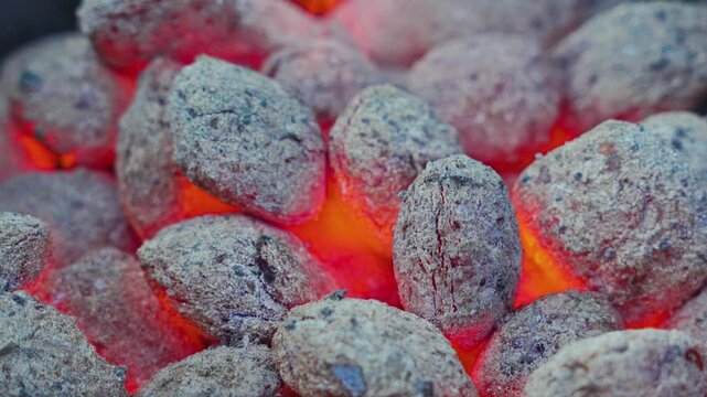A slow-motion video showcasing glowing coals in a barbecue grill, with embers radiating heat and a fiery glow, ideal for outdoor cooking scenes