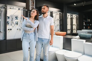 Obraz premium Young couple choosing lavatory pan standing together in the building shop with sanitary ceramics