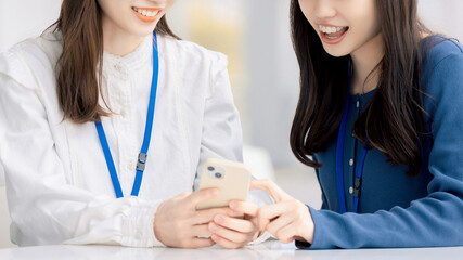 スマホを見て話す2人の女性・ビジネスウーマン