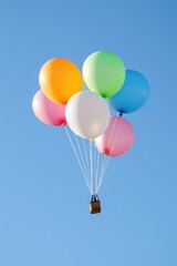 Fototapeta premium A hot air balloon with a basket full of colorful balloons. The balloons are of different colors and sizes, and the basket is filled with them. The balloon is flying high in the sky