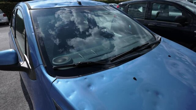 car body damaged by hail. hail damage on the hood and roof of the car
