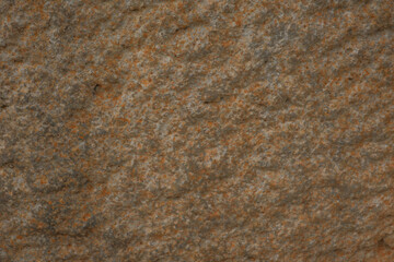 Close-up of a natural stone texture with earthy tones of orange and gray. Ideal for backgrounds,...
