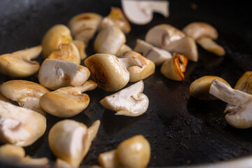 Mushrooms are fried in a pan until golden brown. Close-up, chosen focus. Background.