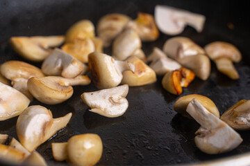 Mushrooms are fried in a pan until golden brown. Close-up, chosen focus. Background.