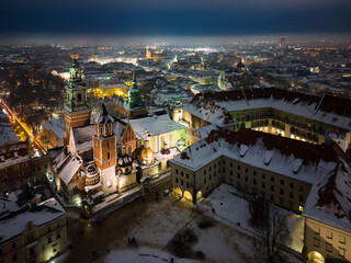 Naklejka premium Aerial view of snowy Wawel castle and Wawel cathedral from a drone on a cold winter night