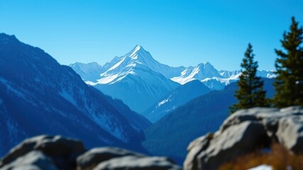Obraz premium A stunning view of a snow-capped mountain range, with a foreground of jagged rocks and pine trees, all under a clear blue sky.