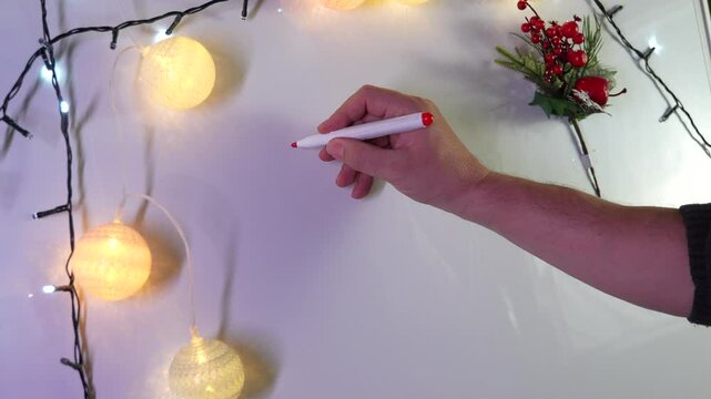 Man writing merry xmas on whiteboard with christmas lights decoration