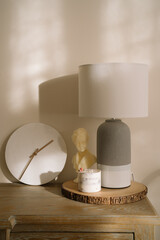 minimalist decor for a living room. A minimalistic sideboard with white marble clock, aesthetic candles and a table lamp. Minimal aesthetic and simplicity concept