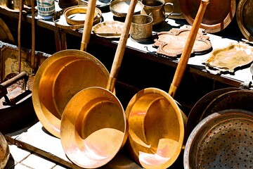 Vintage brass frying pans with wooden handles at a flea market in Yerevan
